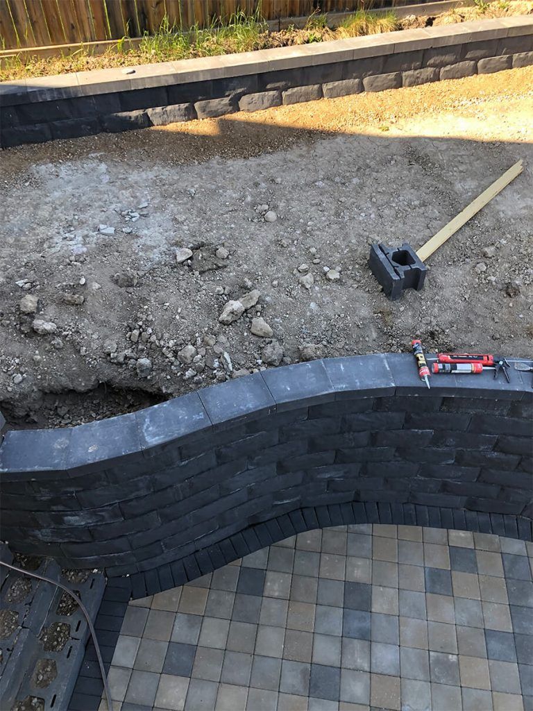 A brick wall is being built on top of a brick patio.