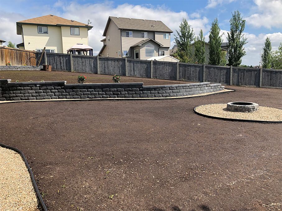 A backyard with a fire pit and a brick wall