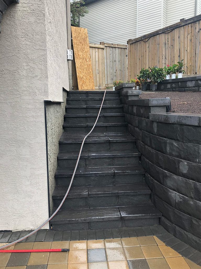 A hose is attached to a set of stairs next to a wall.