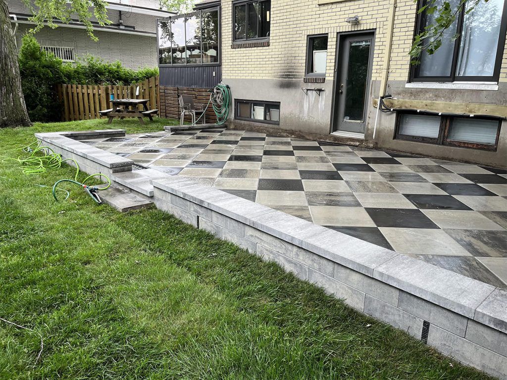 There is a checkered patio in the backyard of a house.
