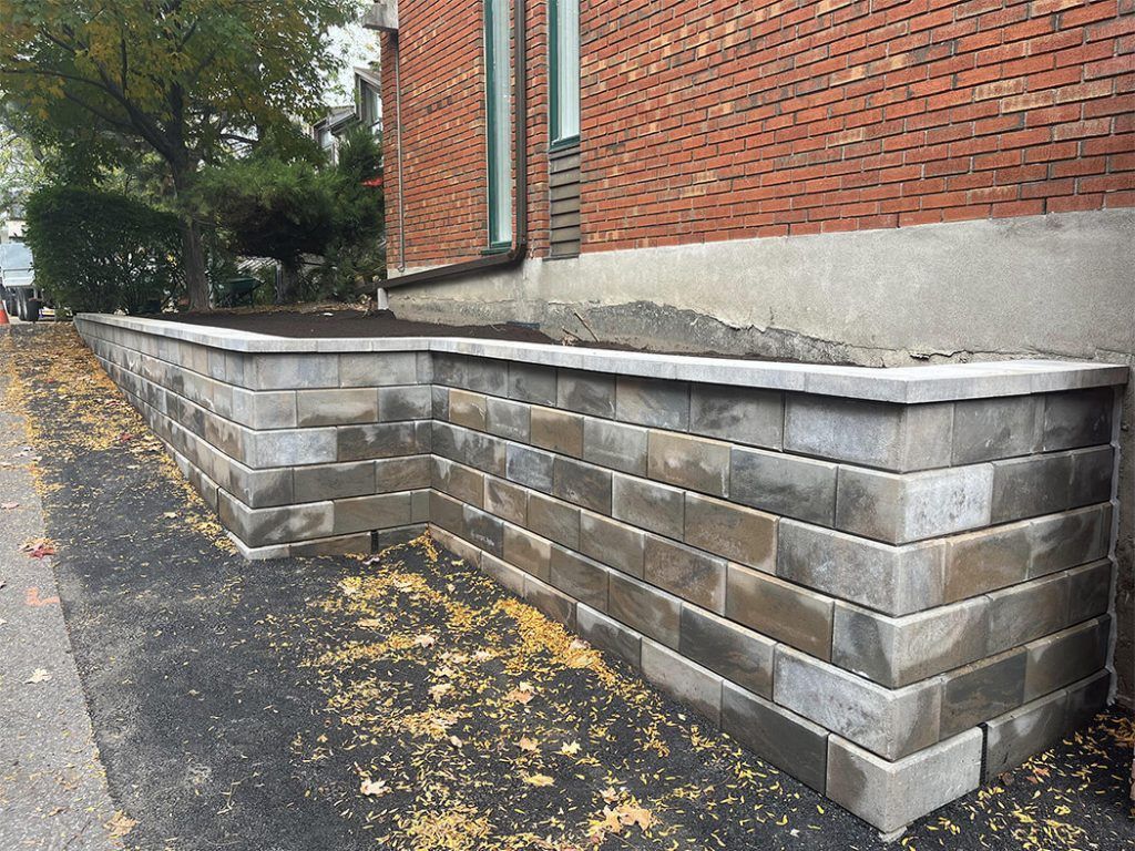 A brick wall is being built in front of a brick building.