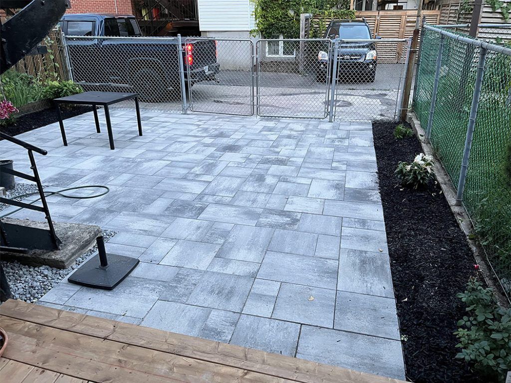 A patio with a table and chairs and a fence in the background.