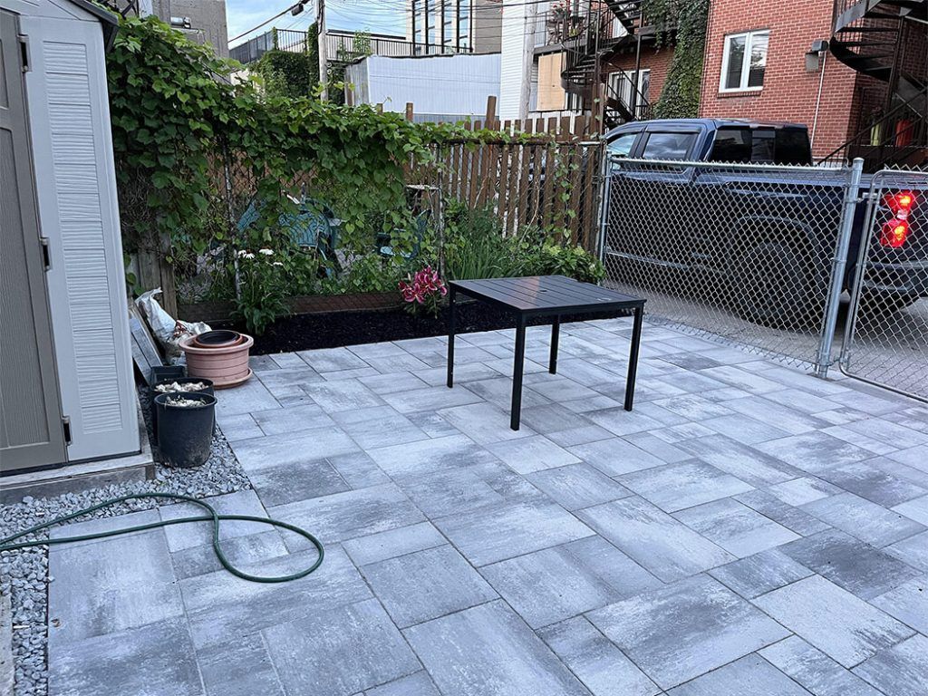 A patio with a table and chairs in front of a chain link fence.