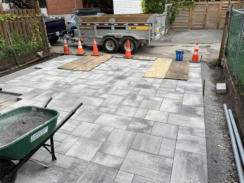 A wheelbarrow is filled with concrete next to a trailer.