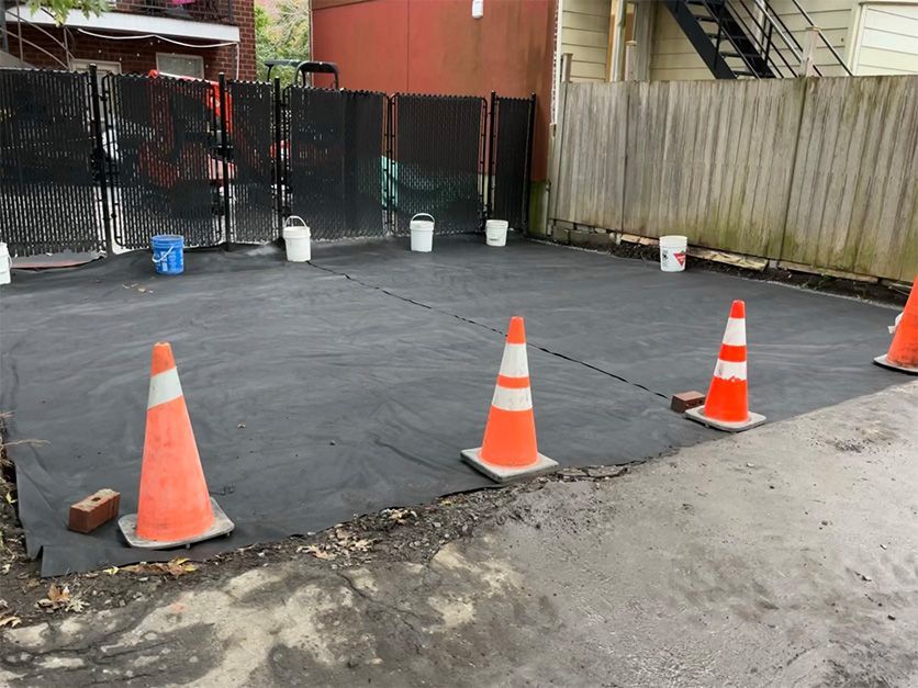 Three orange and white traffic cones are sitting on the side of a road.