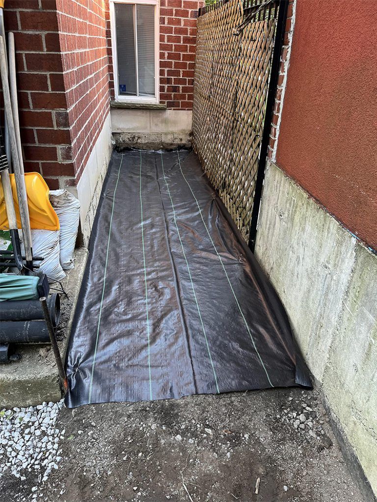A black tarp is covering a sidewalk next to a brick building.