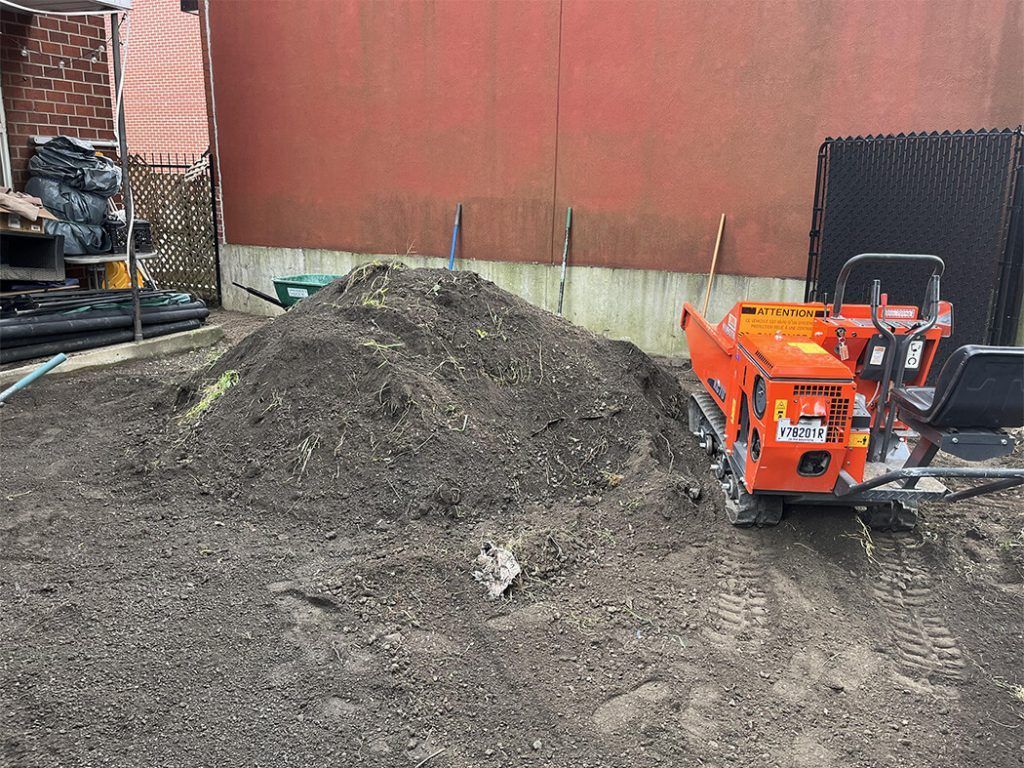 A small orange bulldozer is sitting next to a pile of dirt.