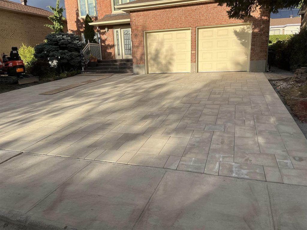A brick house with a concrete driveway in front of it.