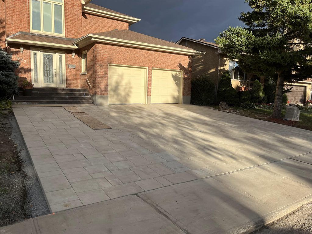 A brick house with a concrete driveway in front of it.