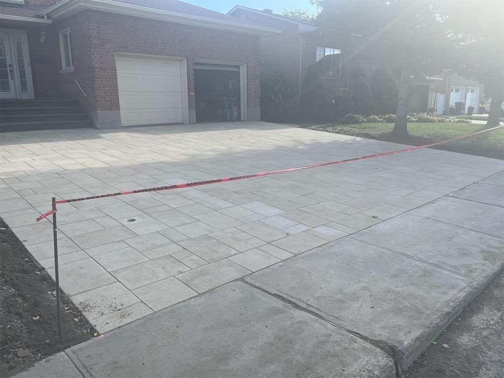 A brick house with a concrete driveway in front of it.