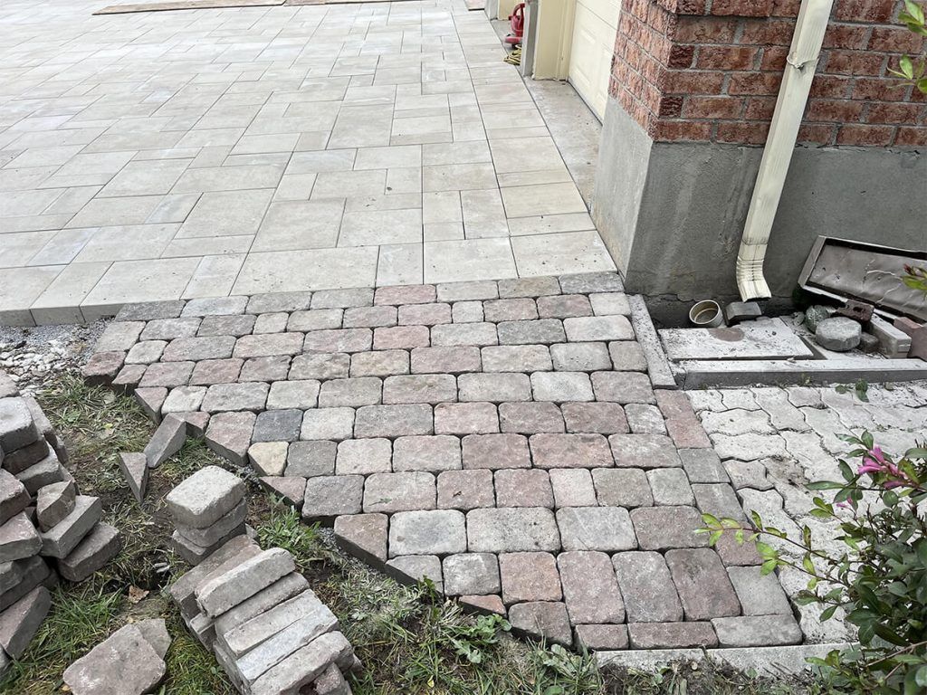 A brick walkway is being built next to a brick building.