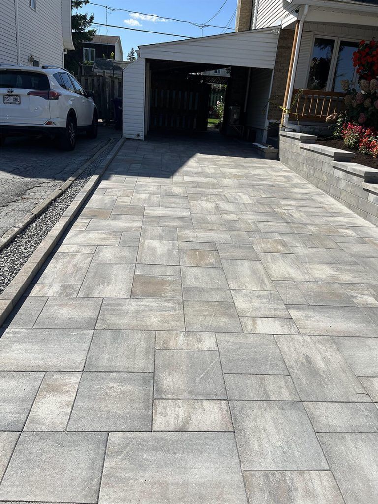 A car is parked in a driveway next to a garage.