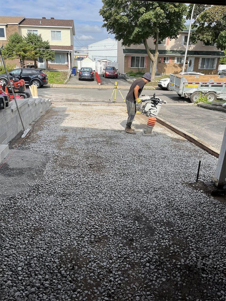 A man is working on a gravel driveway in a parking lot.