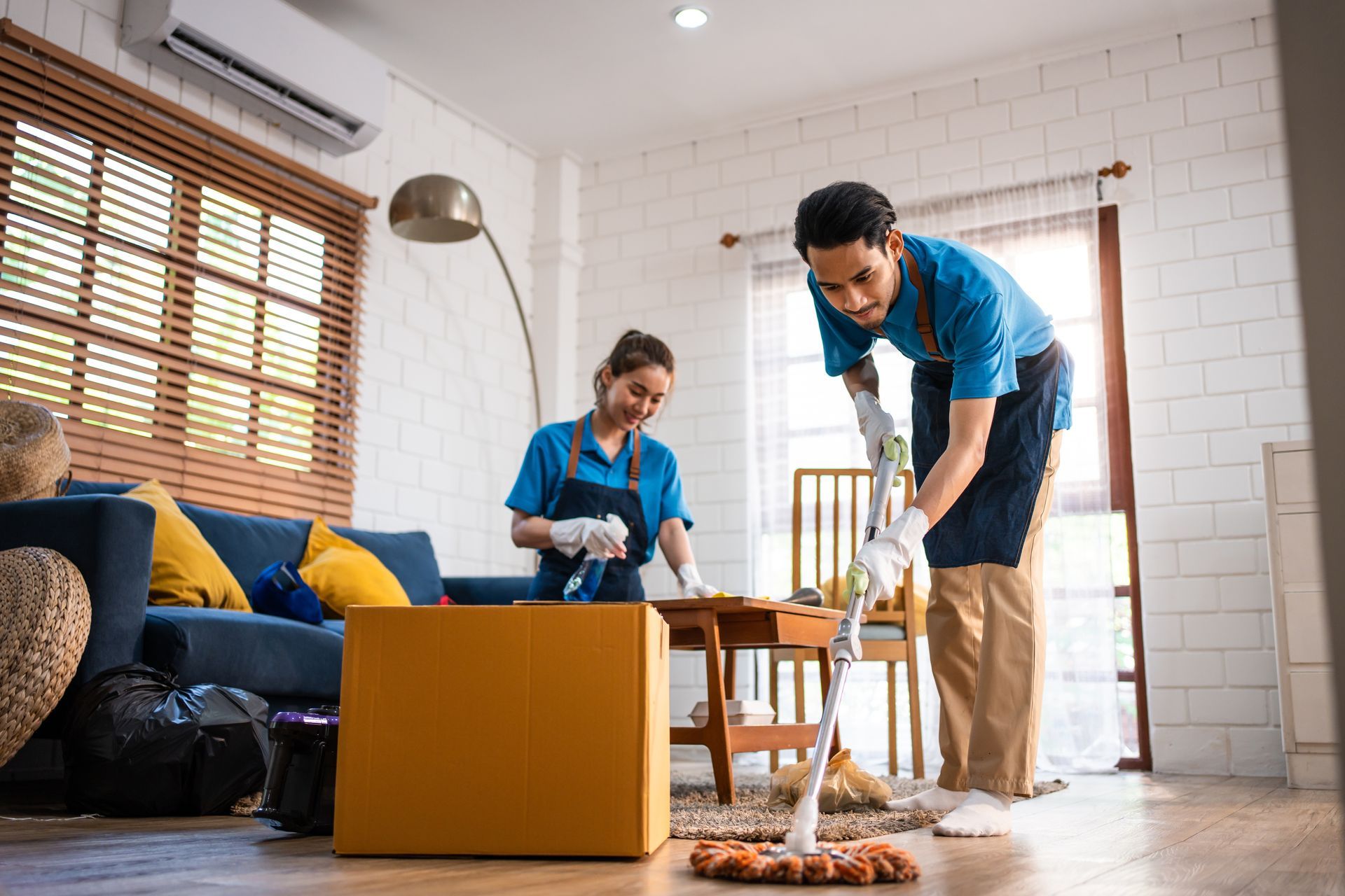 A man and a woman are cleaning a living room.