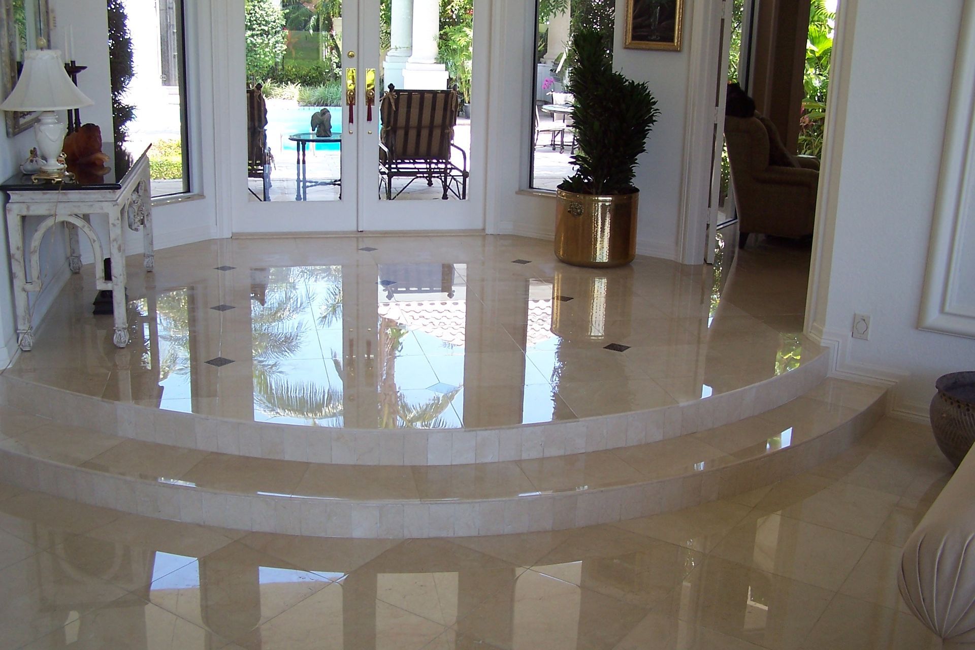 Polished marble flooring in a luxury home. Curved steps lead to a doorway with outdoor seating visible.