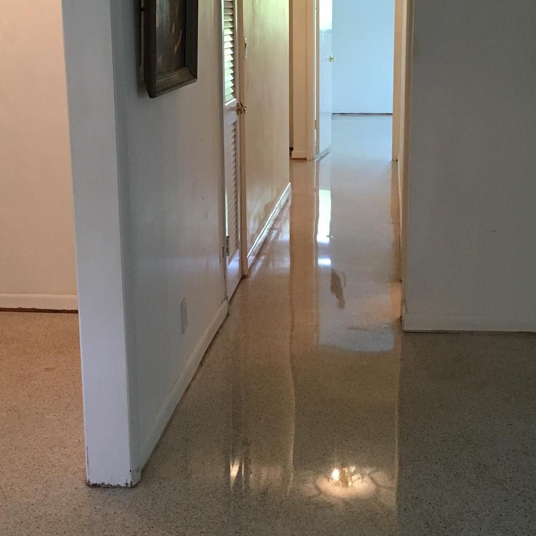 Hallway with polished concrete floor, light reflecting. White walls and door frame.
