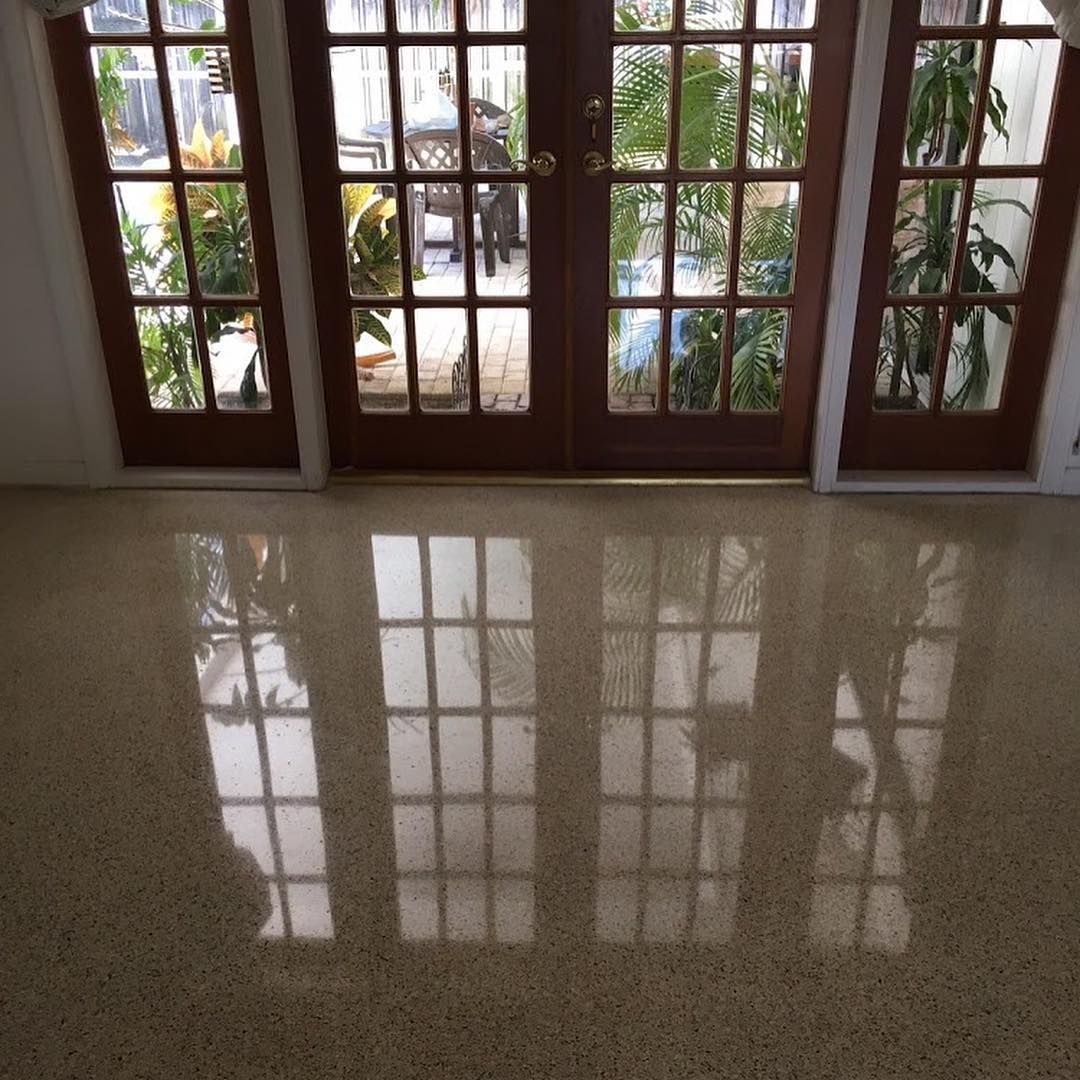 Polished terrazzo floor reflecting light from French doors.