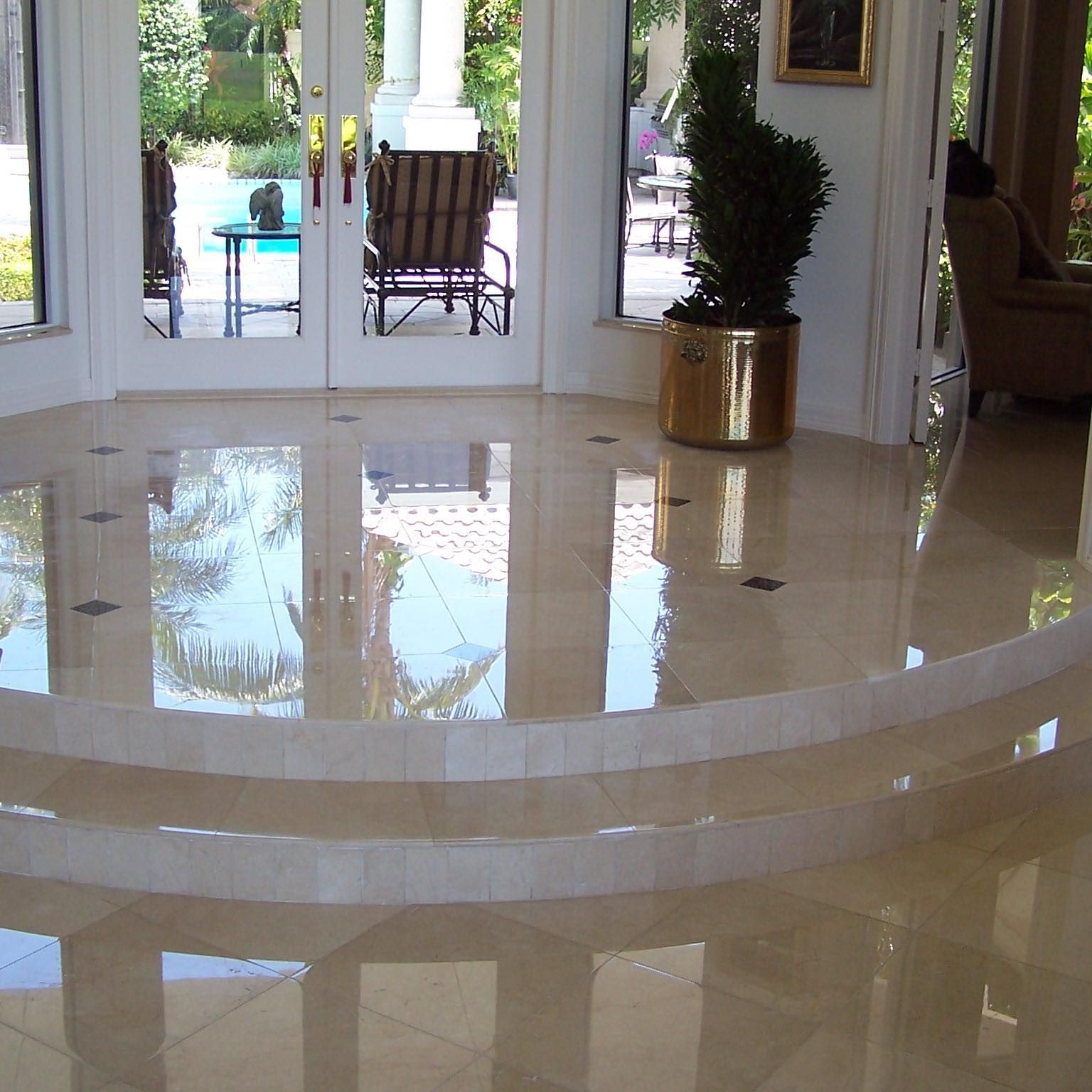 Shiny marble floor with reflected outdoor scene, leading to double doors and a potted plant.