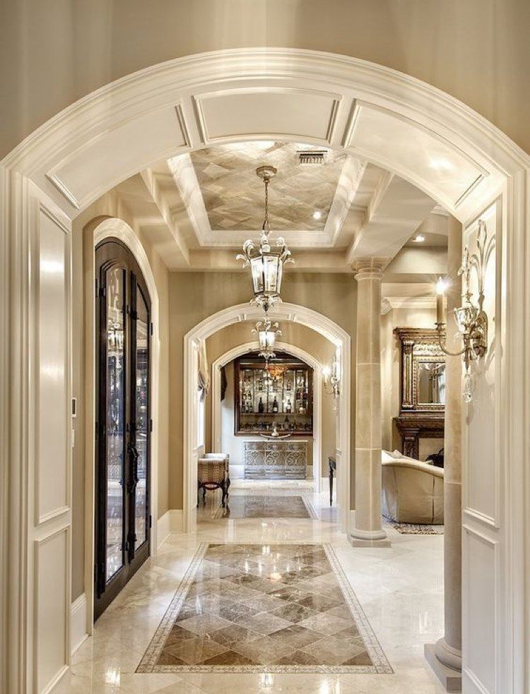 Elegant hallway with arched doorways, marble floor, and chandelier lighting.