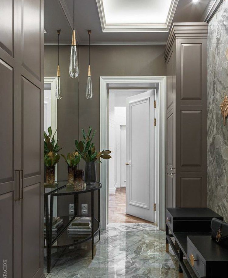 Narrow hallway with gray cabinets, marble floor, and decorative pendant lights.
