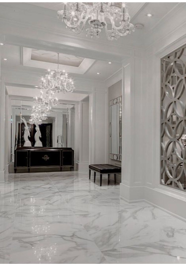 Elegant hallway with marble floors, chandeliers, and decorative mirror panels.