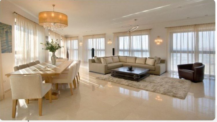 Spacious living room with a dining area, beige sectional, and large windows with sheer curtains.