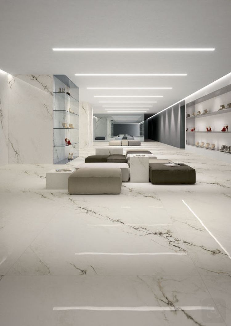 Marble-floored luxury retail space with neutral-toned seating and display shelves, bright lighting.