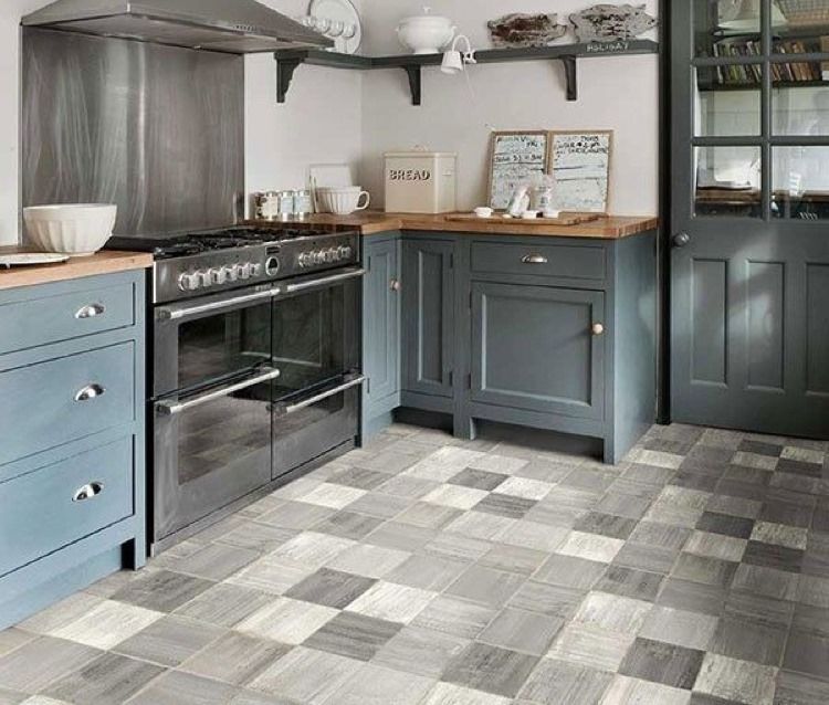 Kitchen with blue cabinets, a stainless steel stove, and checkerboard floor tiles in shades of gray.