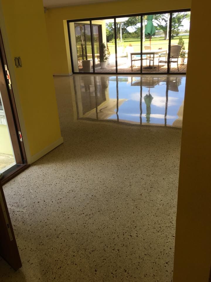 Room with light terrazzo floor and sliding glass doors reflecting the outdoors. Yellow walls.