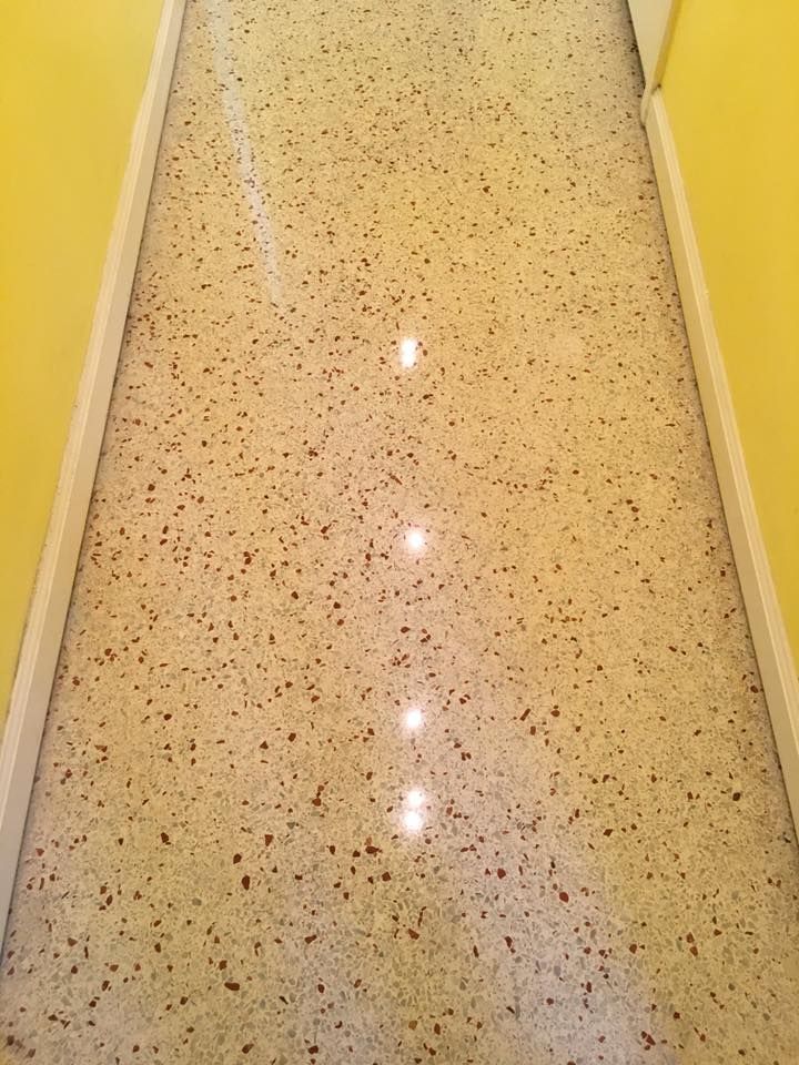 Narrow hallway with polished terrazzo floor, yellow walls, and white trim.