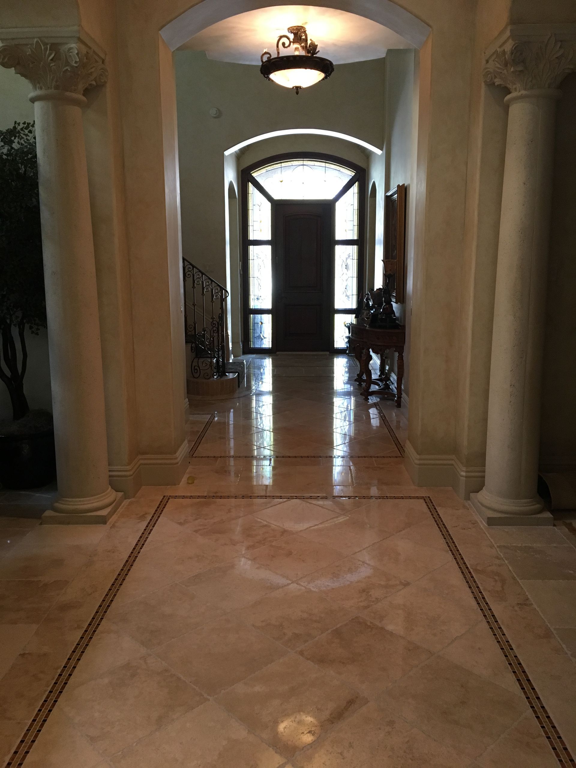 Hallway with marble floors, pillars, and a dark wooden door at the end.