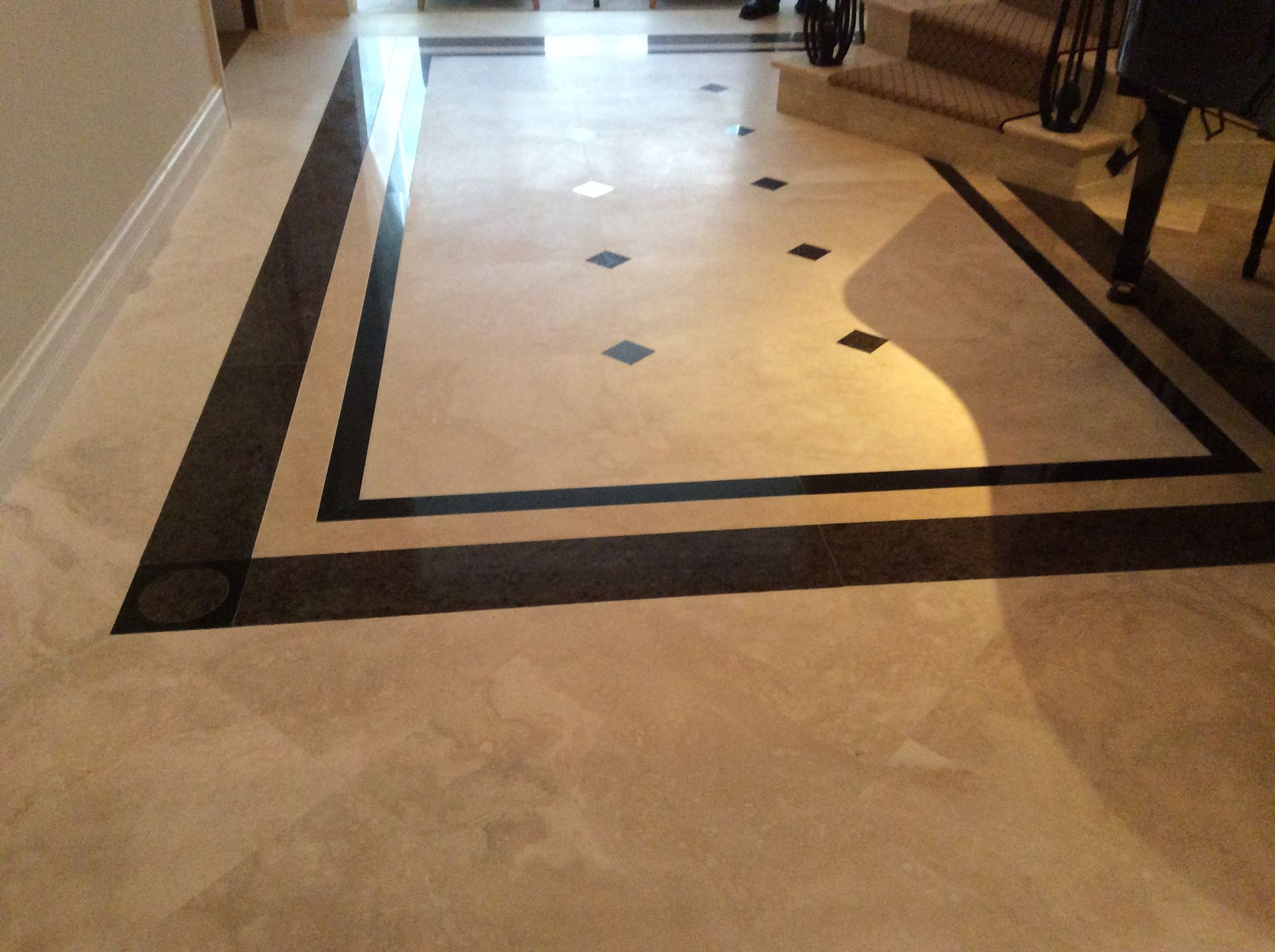 Light-colored marble floor with a black border and accents, leading towards stairs.