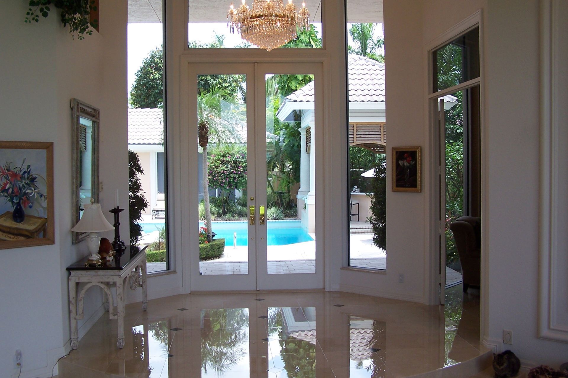 Elegant foyer with marble floor, double glass doors open to a pool.