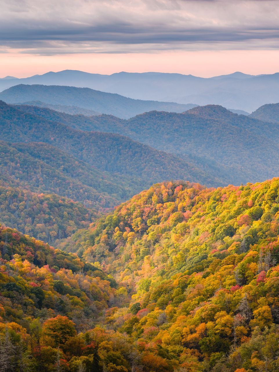 A wooden walkway leading to a gazebo overlooking a body of water at sunset.