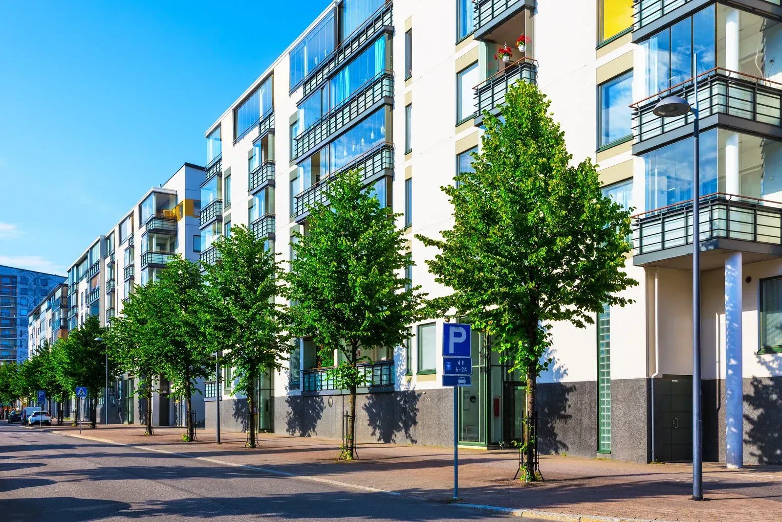 A row of apartment buildings with trees in front of them.