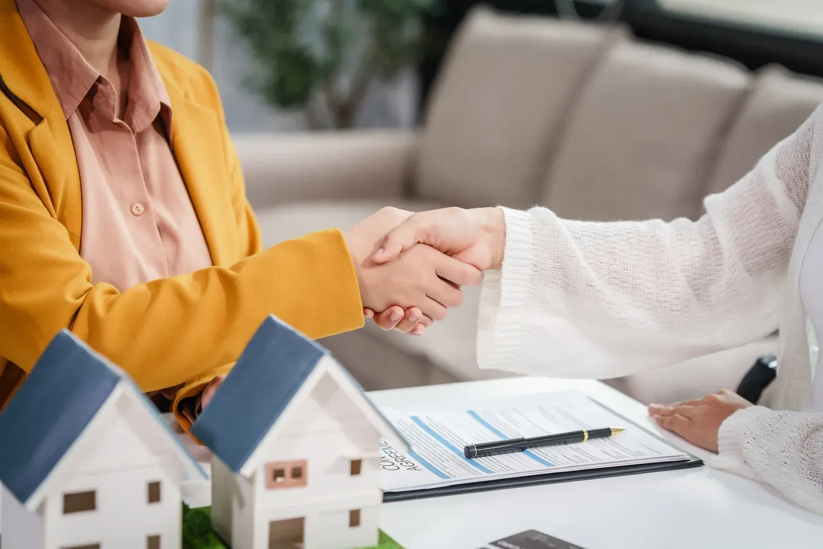 A woman is shaking hands with a real estate agent while sitting at a table.
