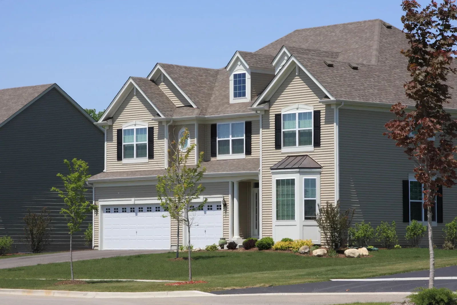 A large house with a gray roof and white garage doors
