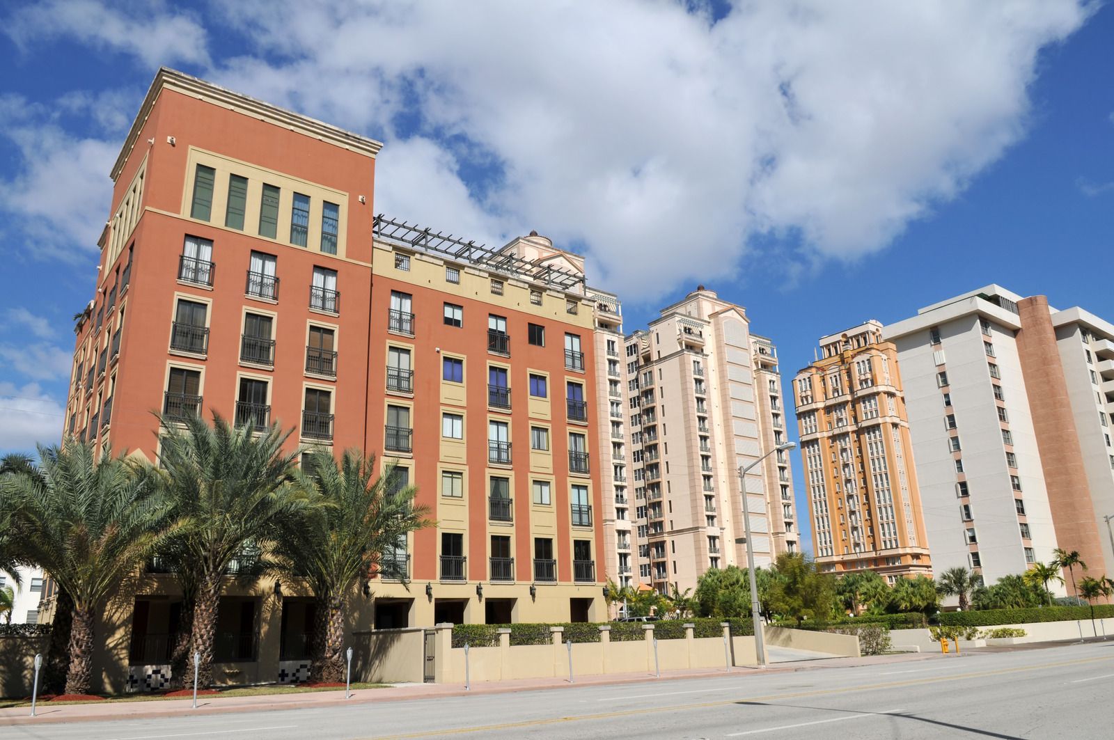 A row of tall buildings with palm trees in front of them