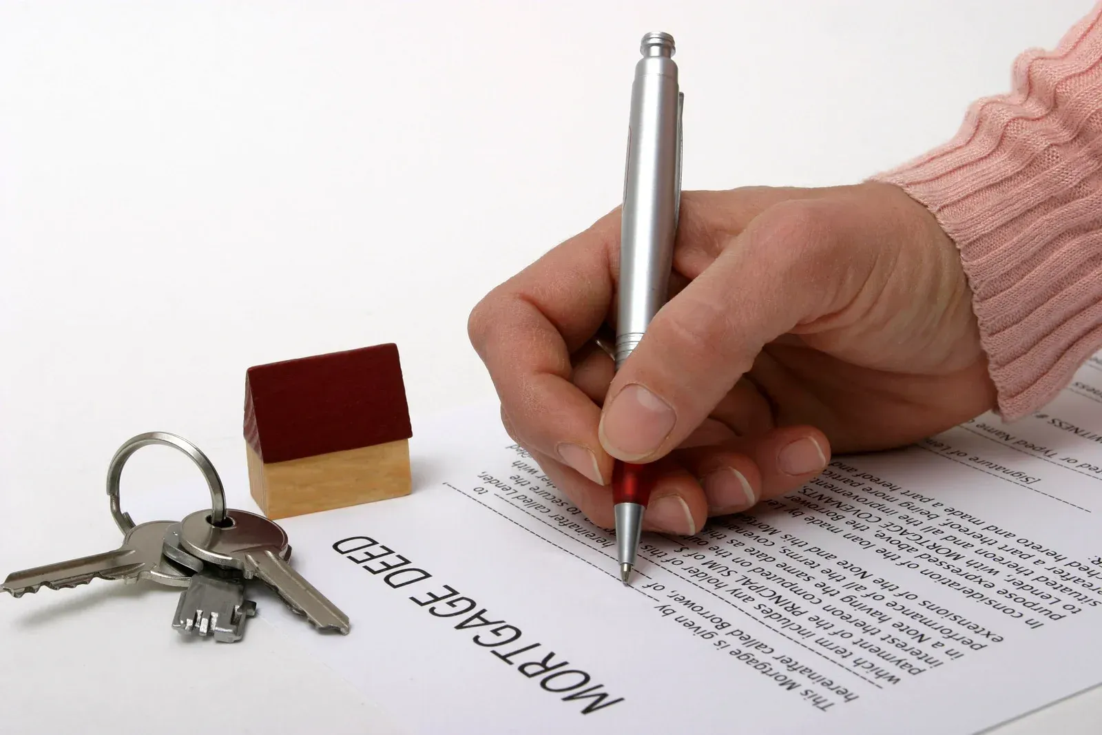 A person is writing on a piece of paper that says mortgage deed