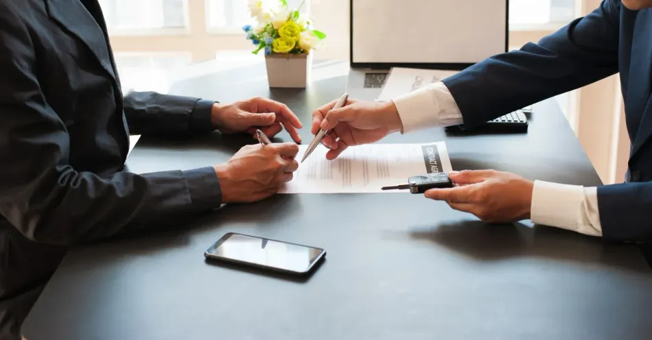 A man and a woman are sitting at a table signing a contract.