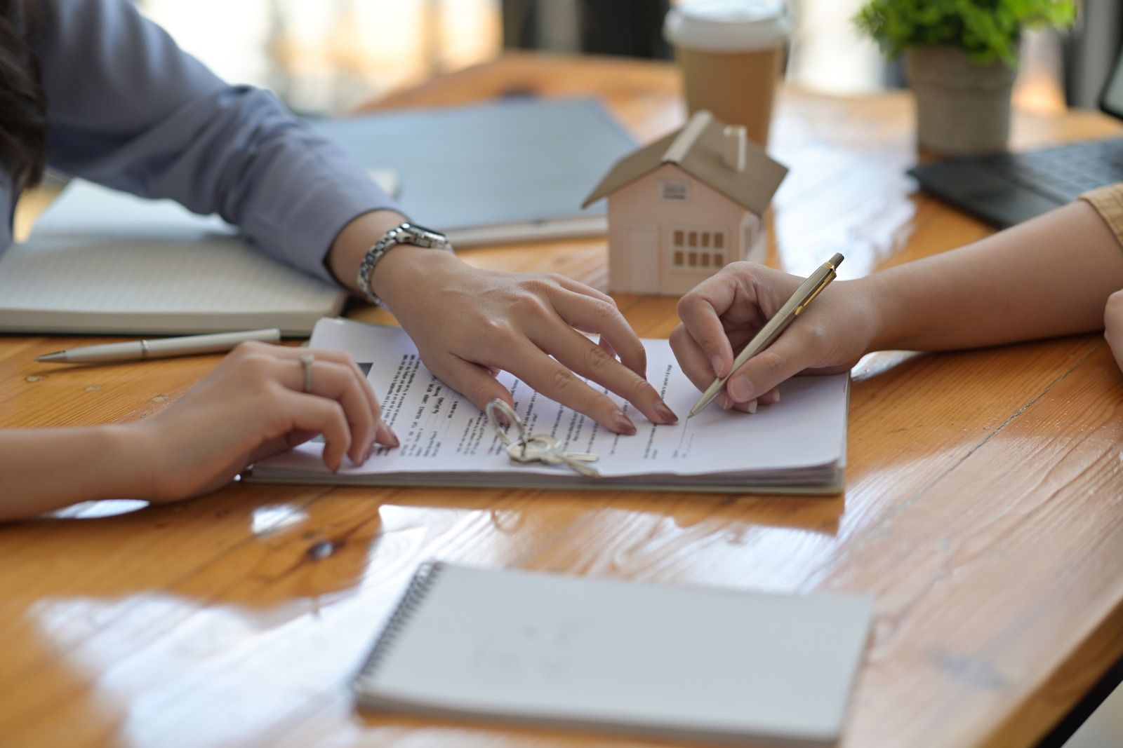 A couple of people are sitting at a table signing a document.