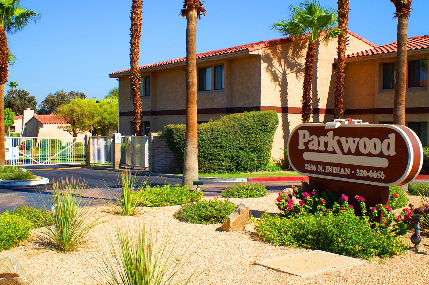 Parkwood sign in front of apartment building with palm trees