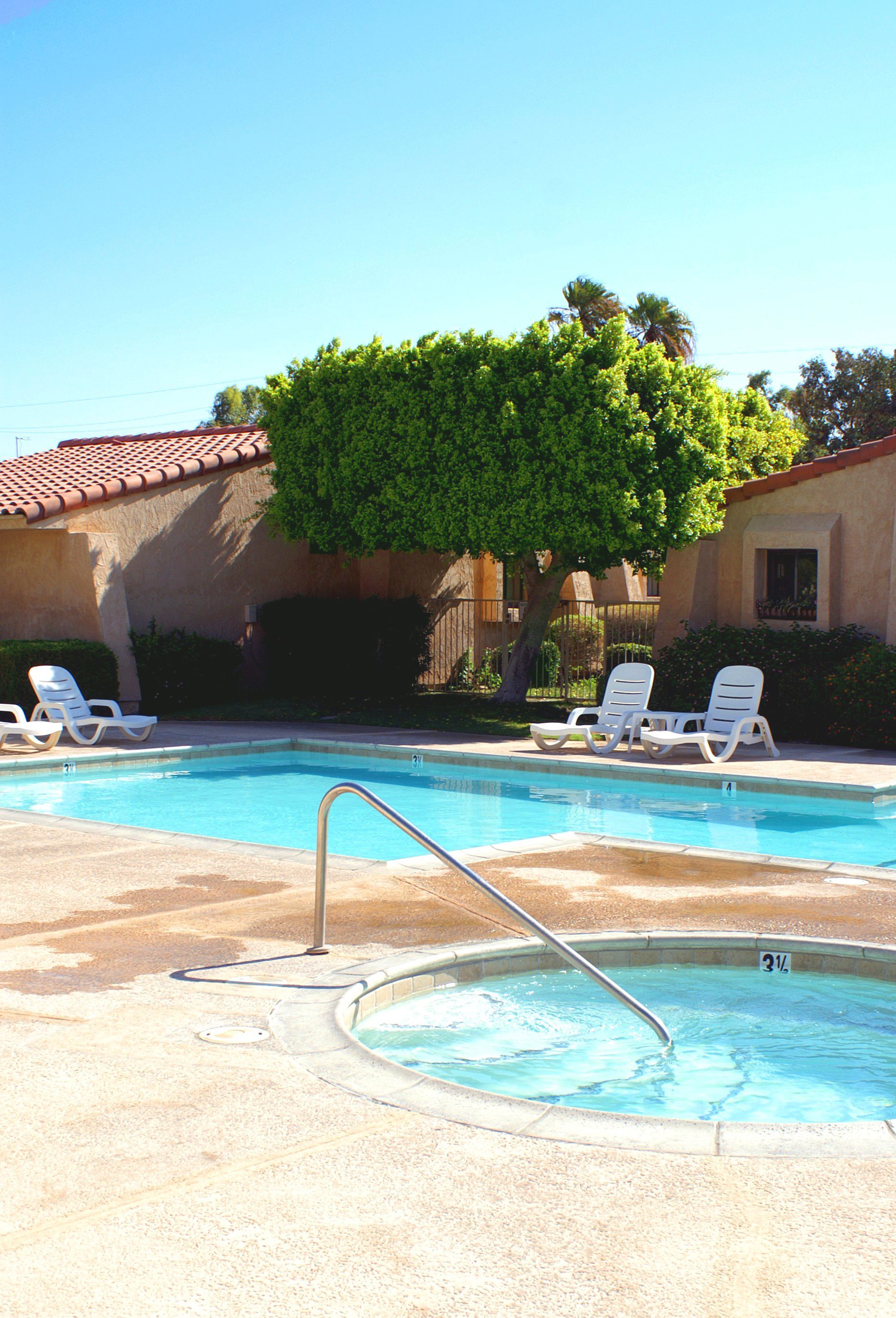 A large swimming pool with a hot tub in the middle of it