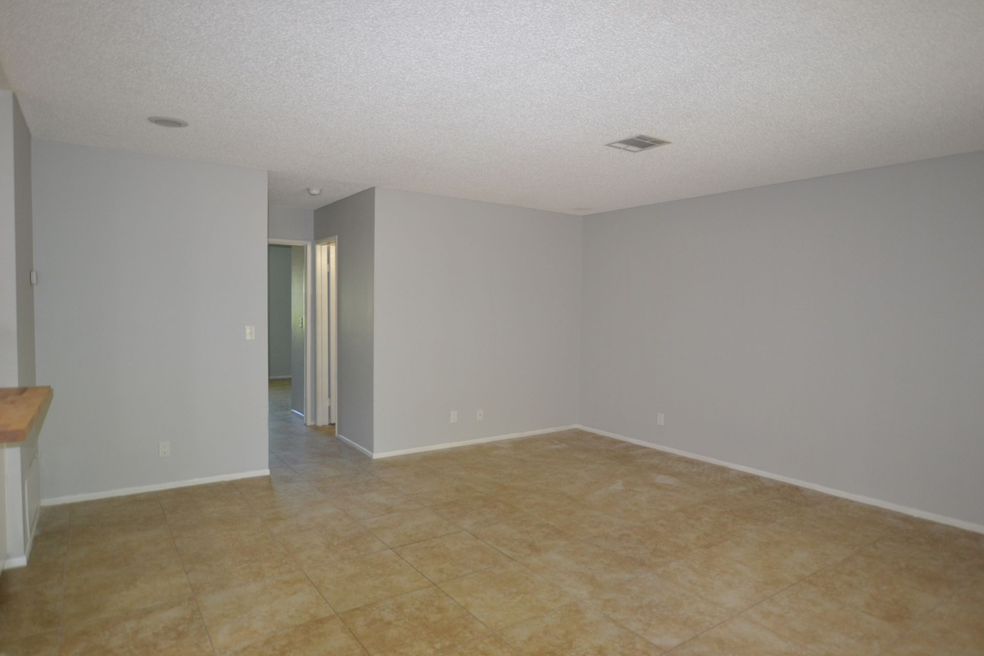 An empty living room with a tile floor and white walls.