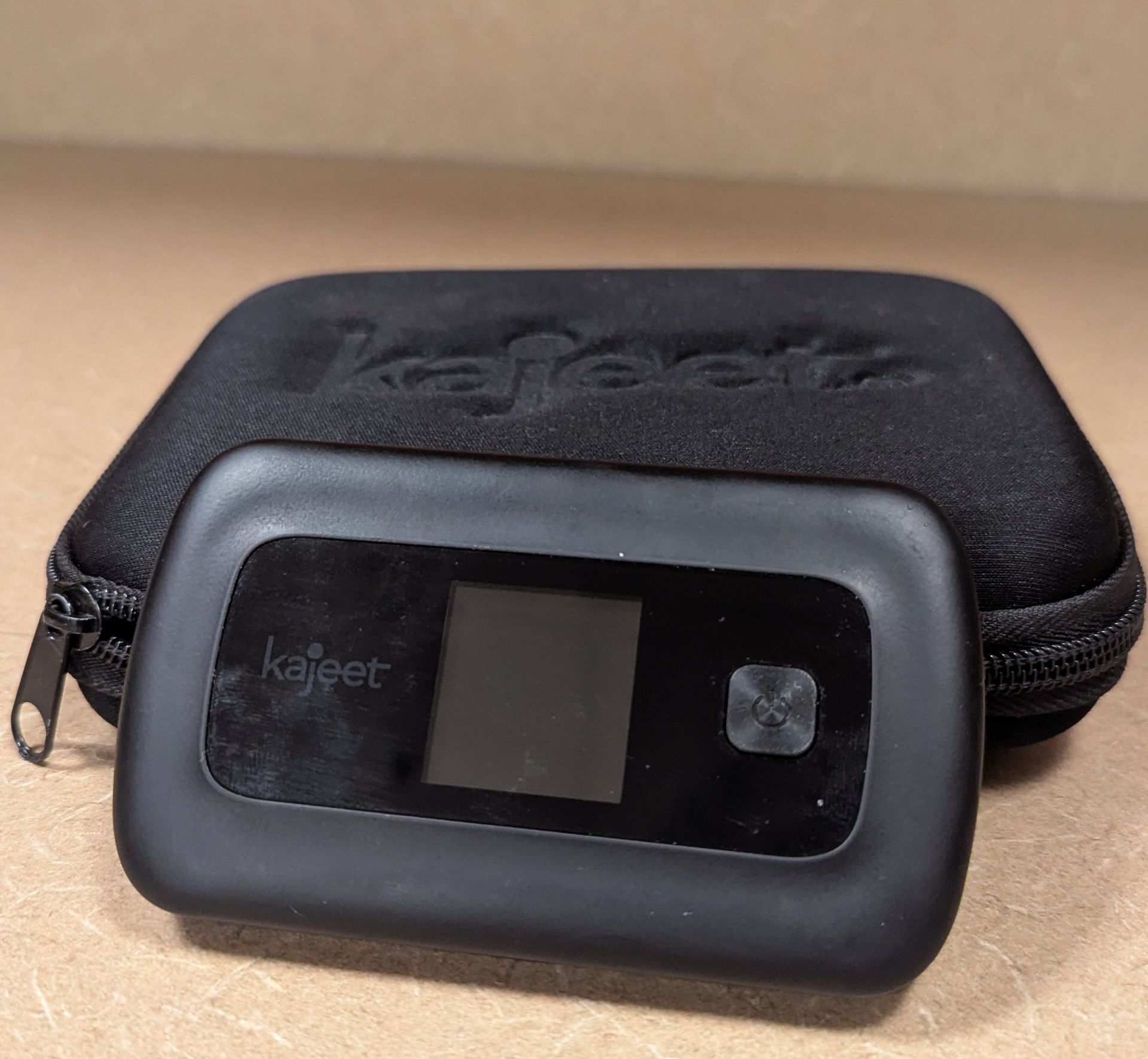 A kajeet hotspot device is sitting against a black case