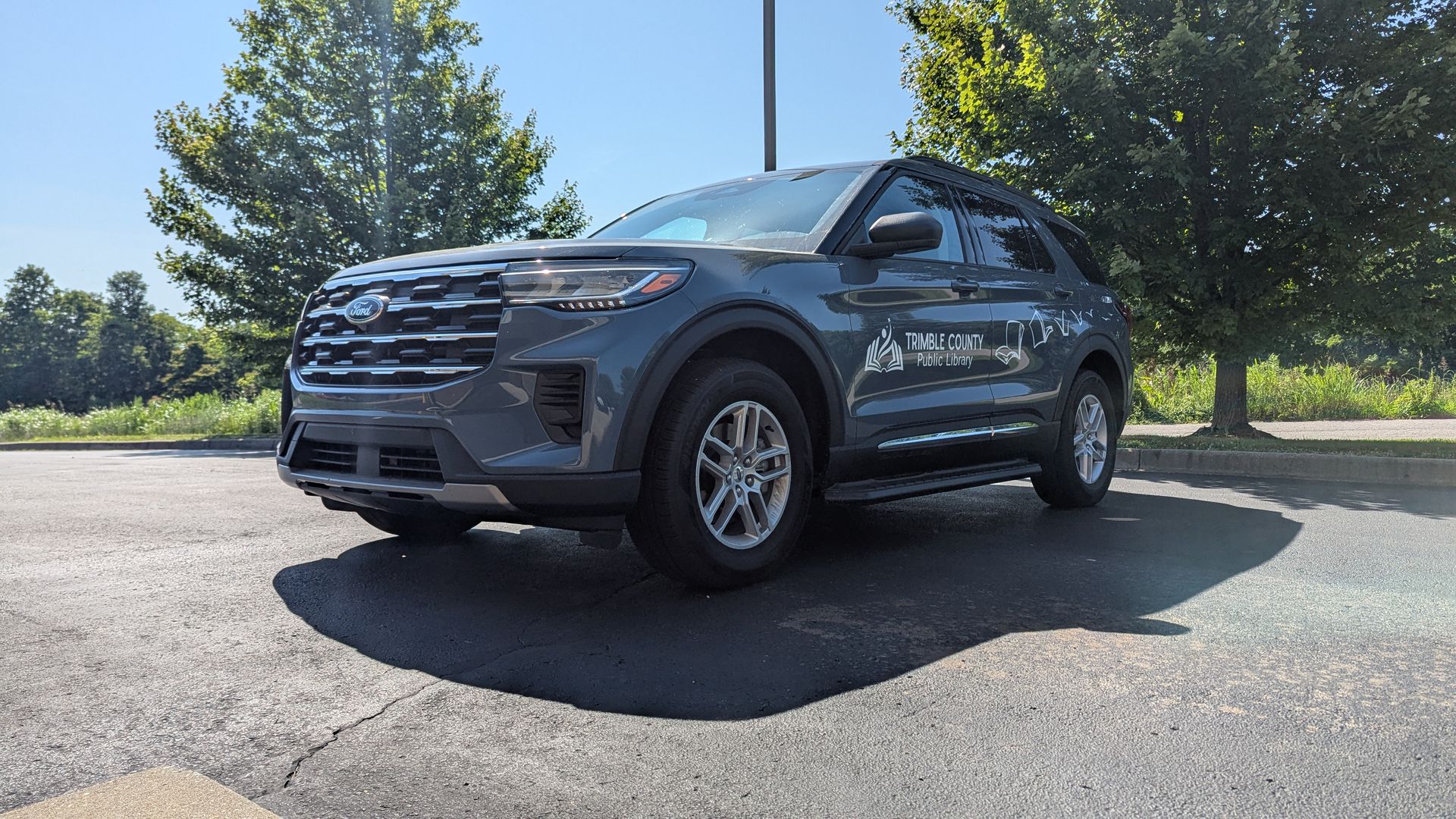a low angle of the library's outreach vehicle, a blue ford explorer with a white library logo on the side.