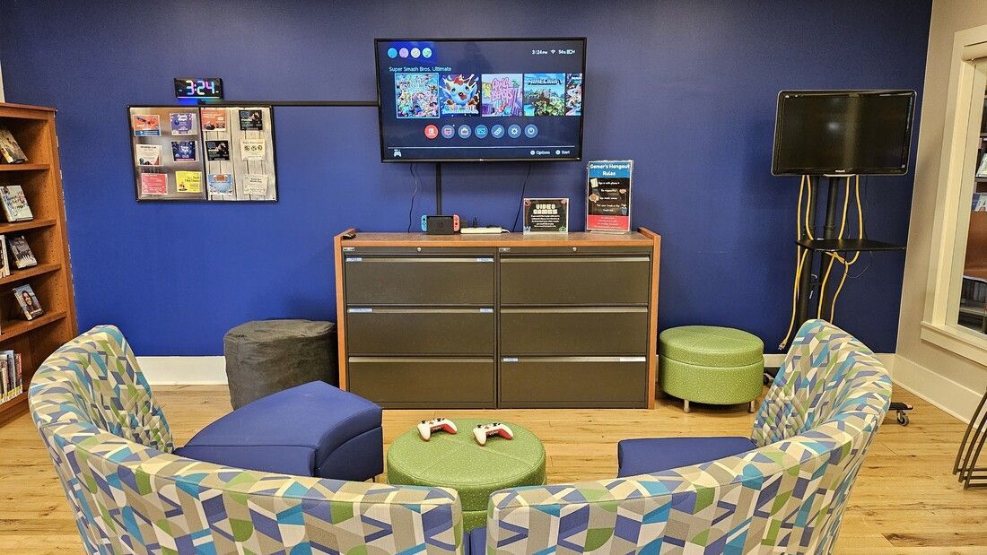 A living room area in the teen room with a large flat screen tv on the wall displaying the nintendo switch home screen