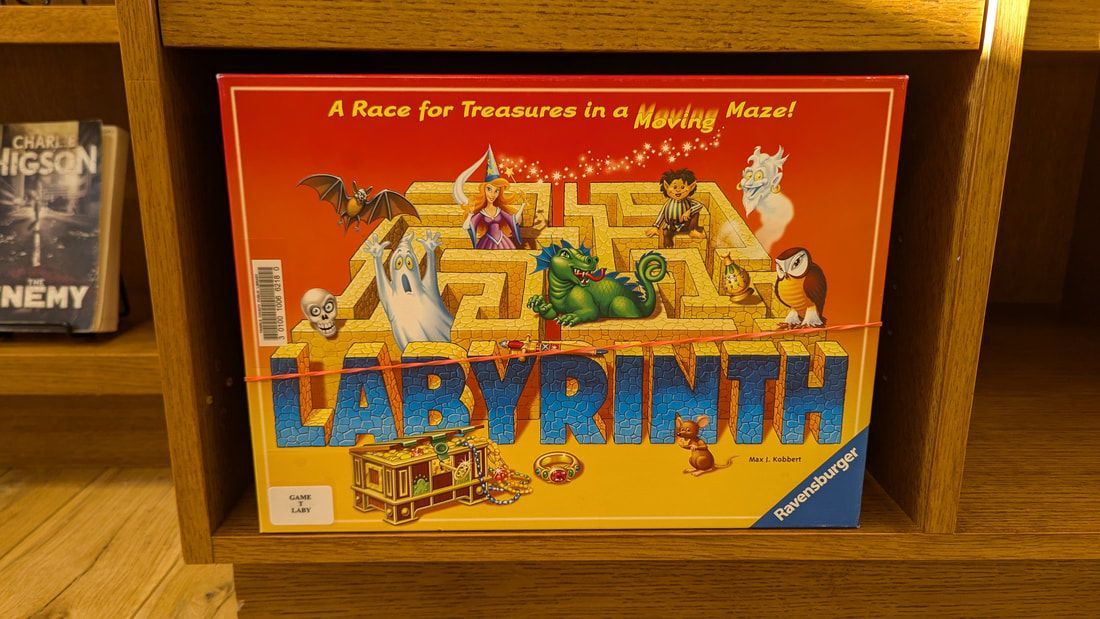 A game called labyrinth sits on a wooden shelf