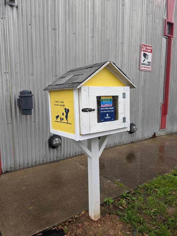 A small yellow and white box with a roof on a white post