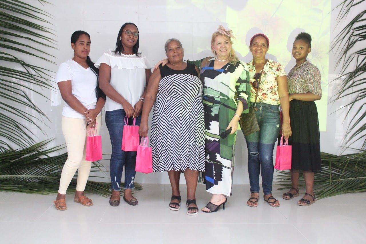 A group of women standing next to each other holding pink bags